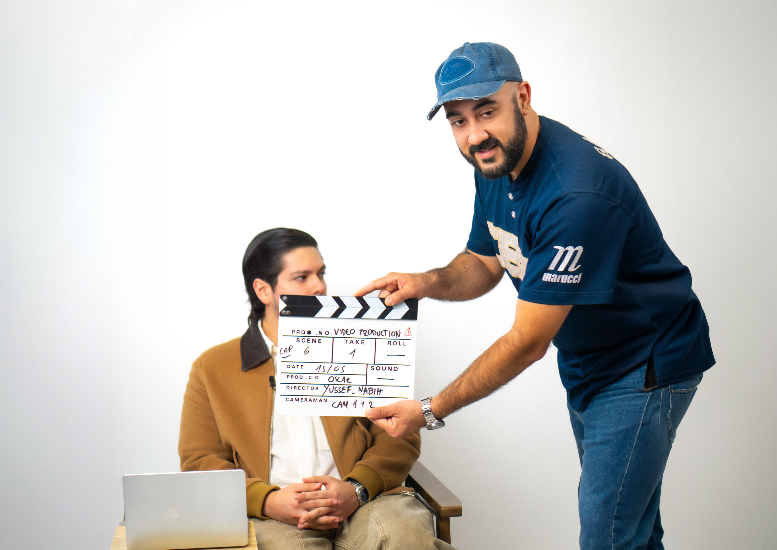 Director de producción marcando la escena 1 con claqueta junto al artista.
