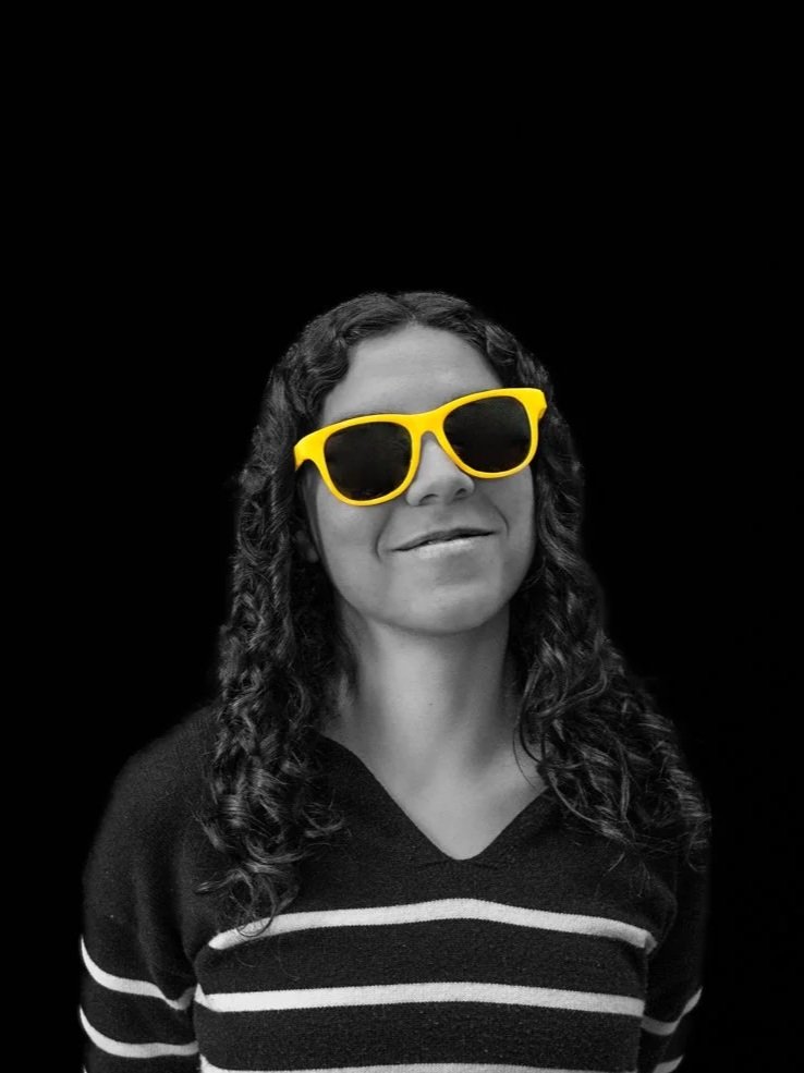 a black and white photo of a woman with yellow glasses