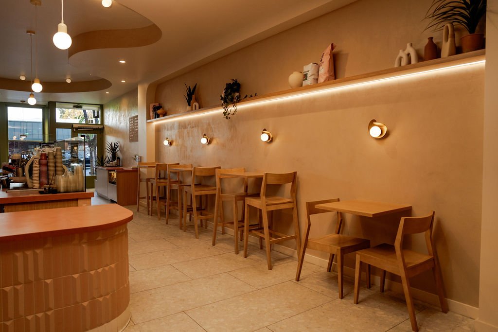 aesthetic coffee shop interior bar seating along wall plaster gold wall sconces