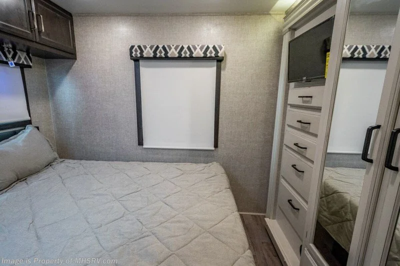 Bedroom with bed, drawers, and TV