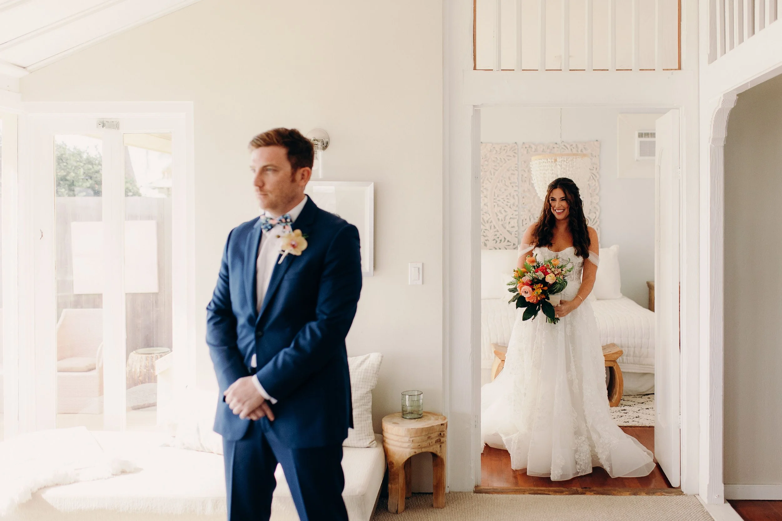 Maui wedding couple during a getting-ready moment, with the groom in a navy suit and the bride holding a colorful bouquet in a white gown