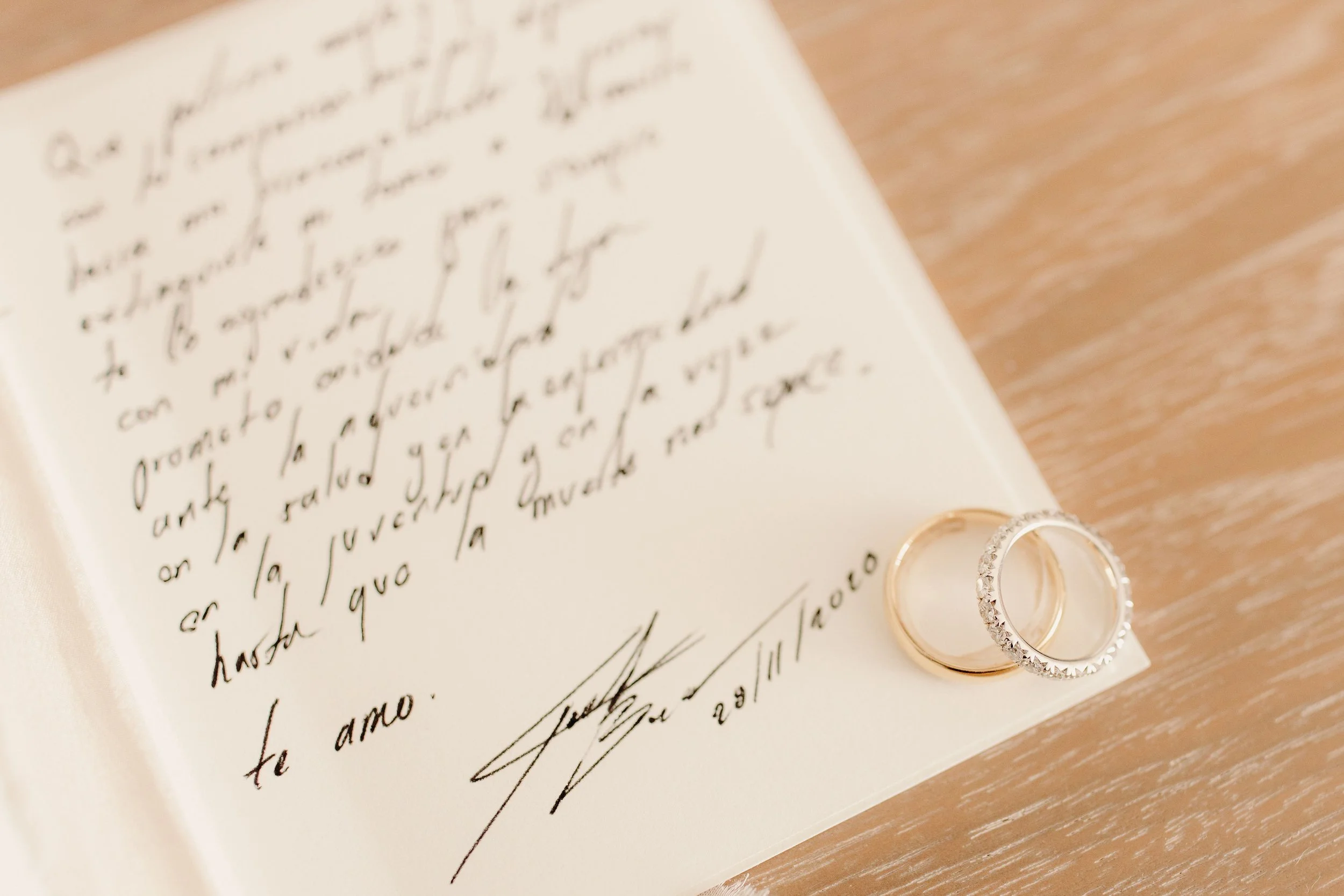 Maui wedding detail of gold and diamond rings resting on a handwritten wedding vow document