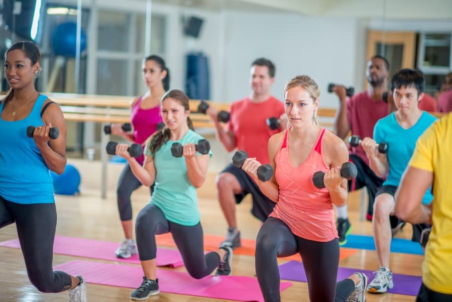 Group of gymgoers on mats holding weights