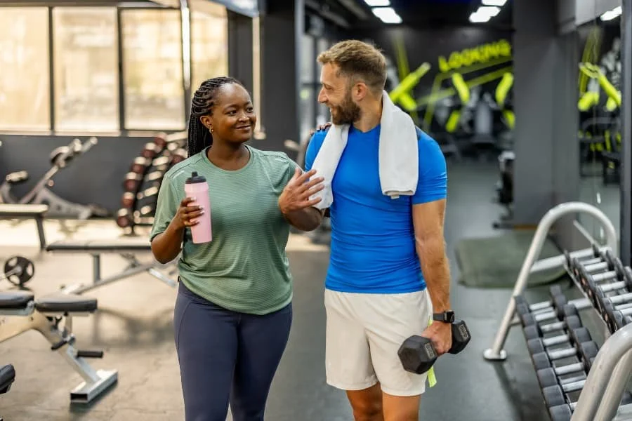 Friends at gym with dumbbells and machines