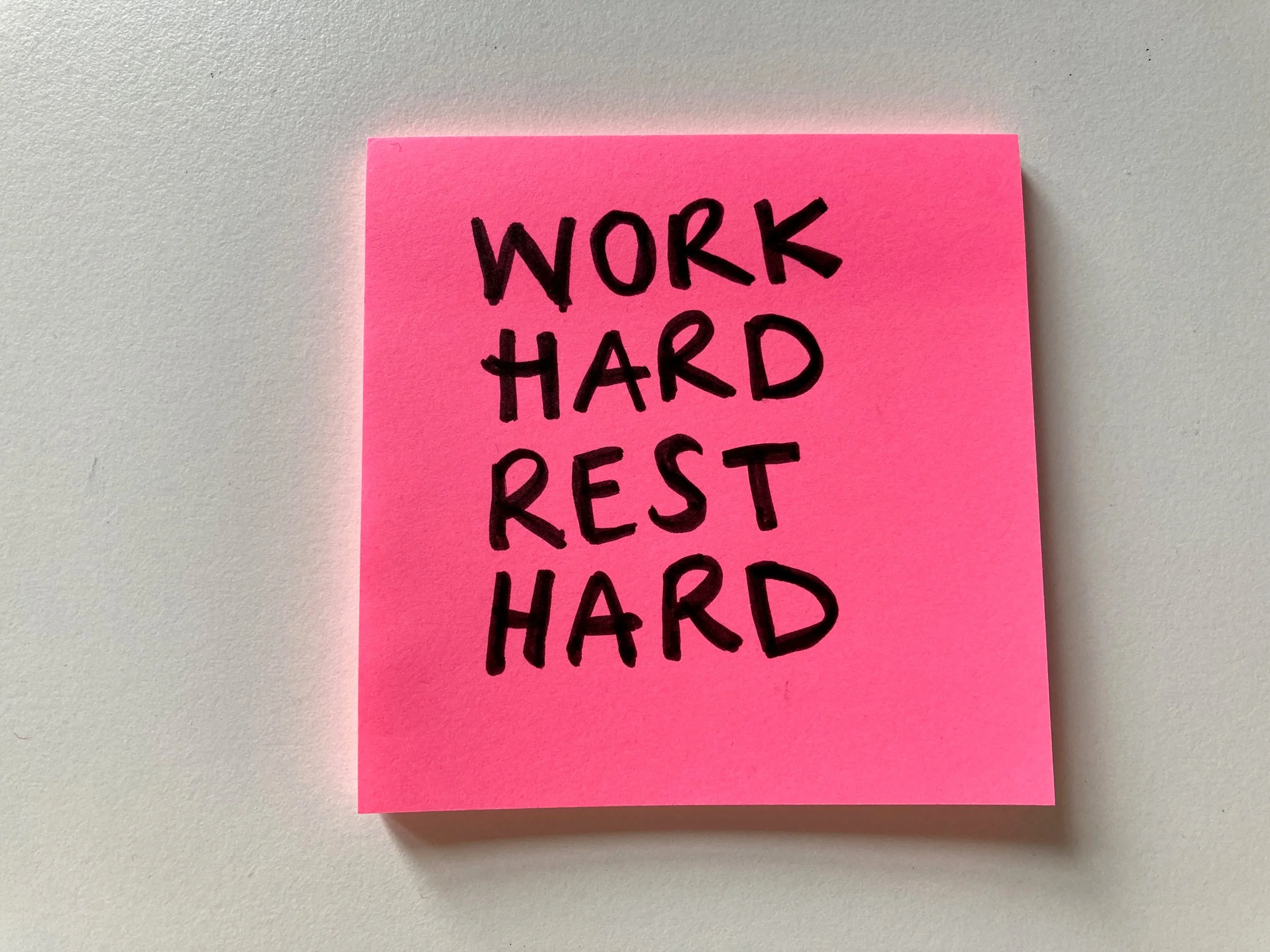 Post it note that says work hard rest hard