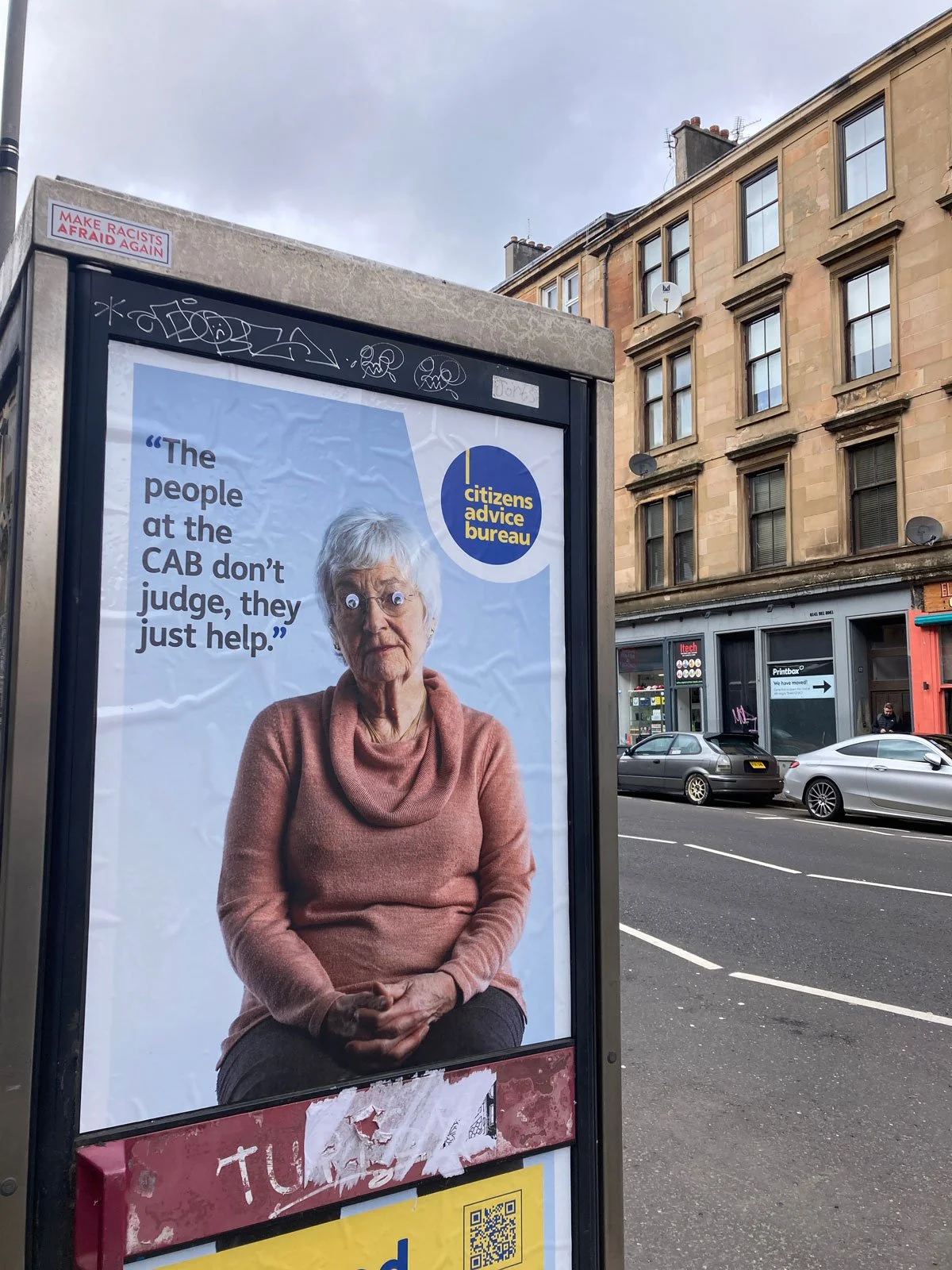 Poster on a phone box with google eyes stuck on it, Glasgow Finnieston