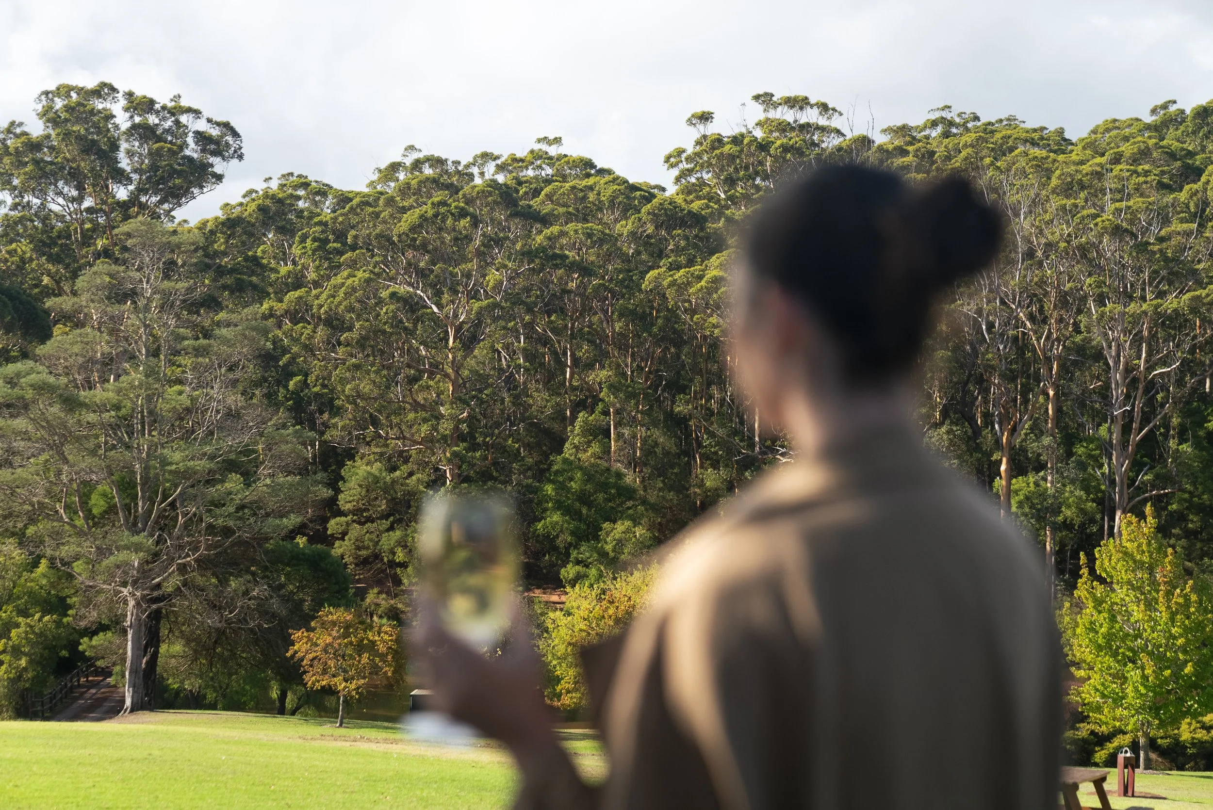 Woman enjoying a glass of wine at a cellar door in Denmark WA overlooking vineyard in the Great Southern region