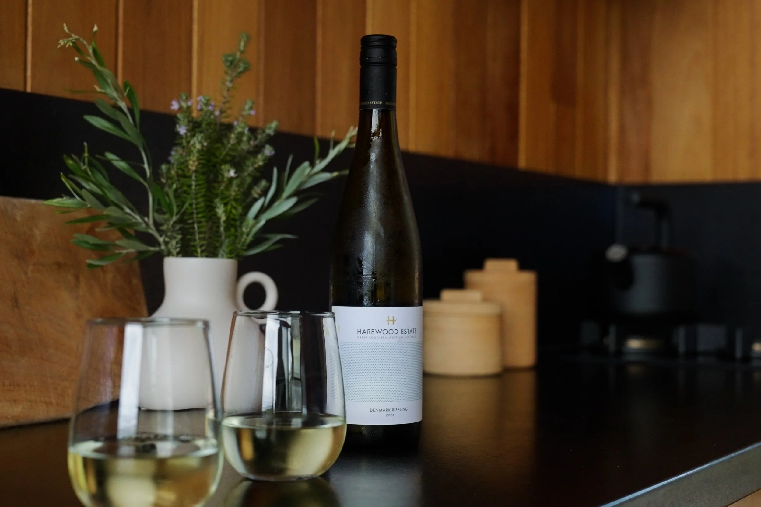 Wine bottle and two glasses inside a cabin at Upland Farm in Denmark WA overlooking farmland in the Great Southern region
