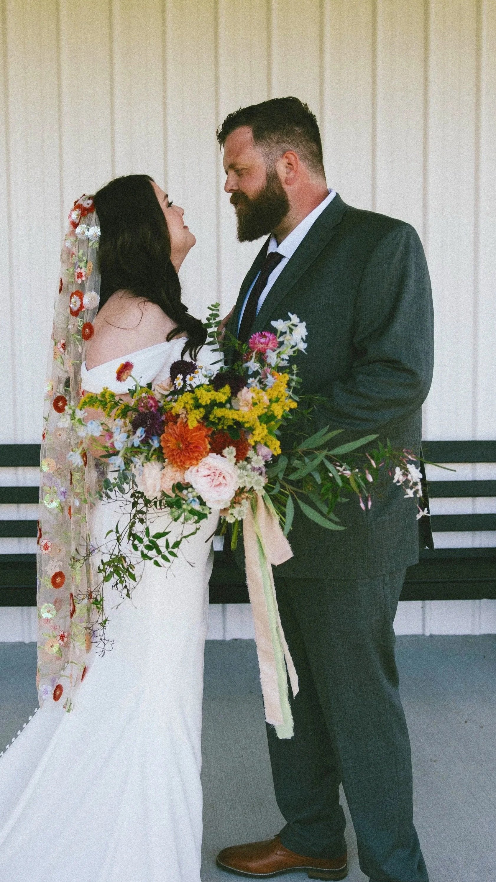Bride and Groom, bride holding a Wildflower bouquet with textured greenery 