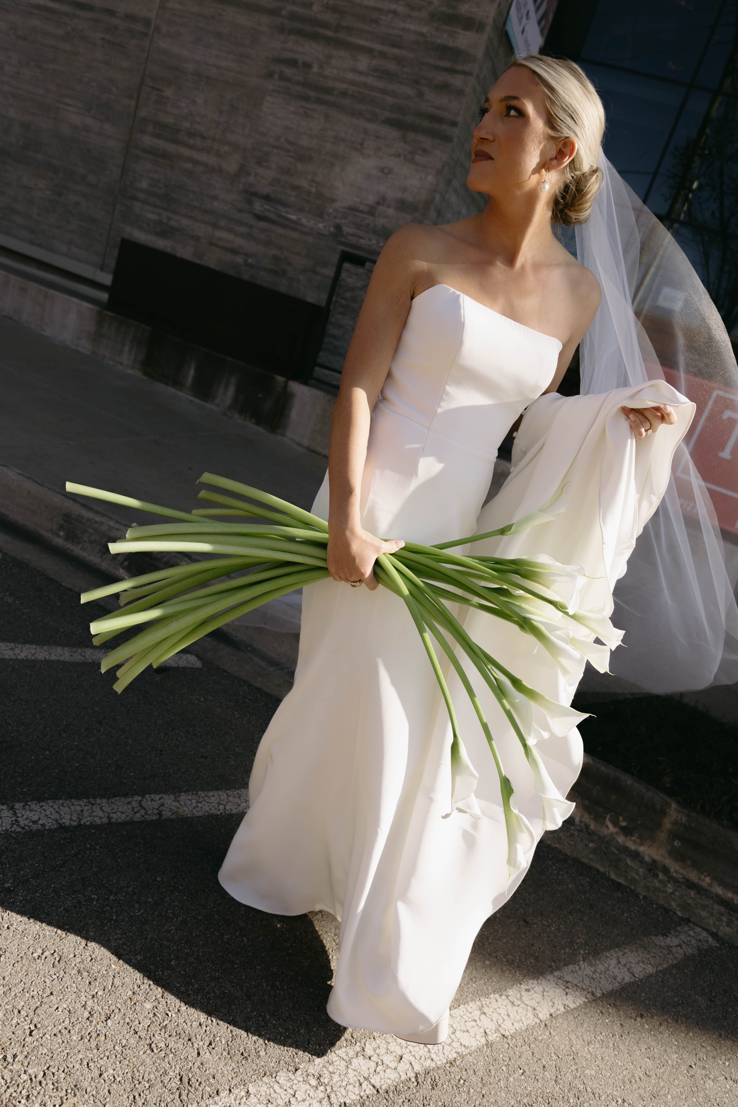 Bride in a white wedding dress holding a bouquet of calla lilies.