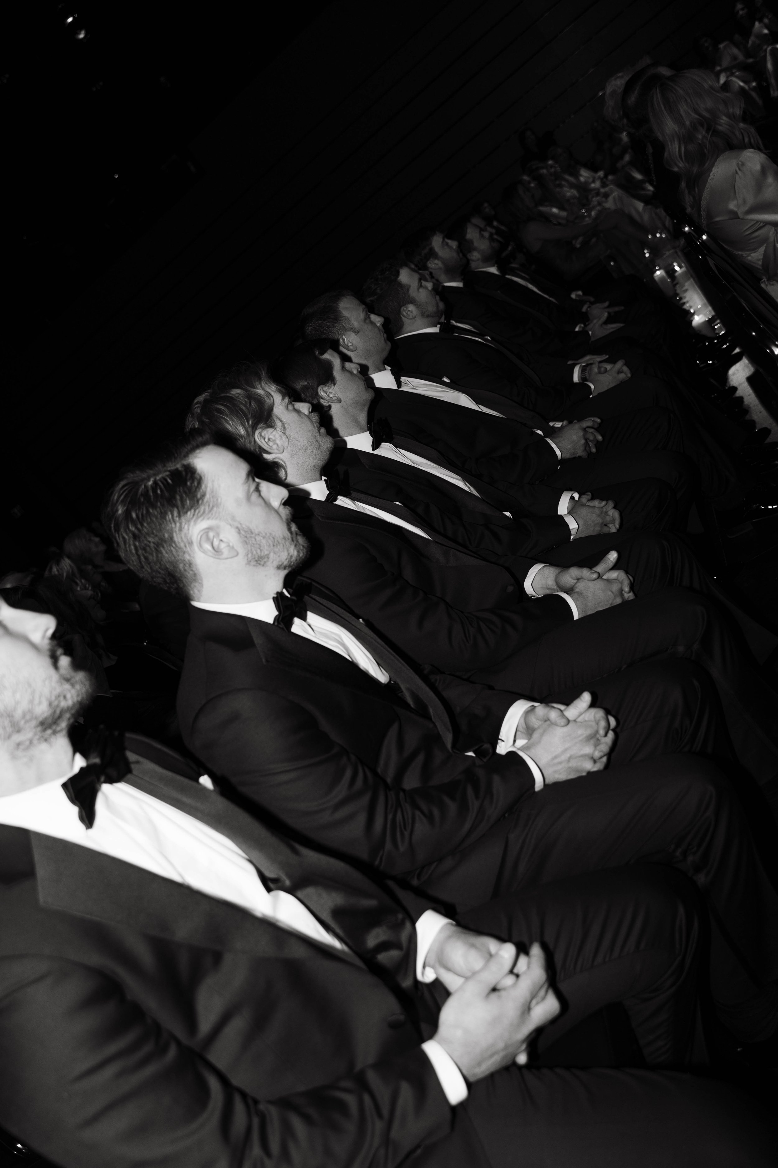 Formal event with men in tuxedos seated in a row