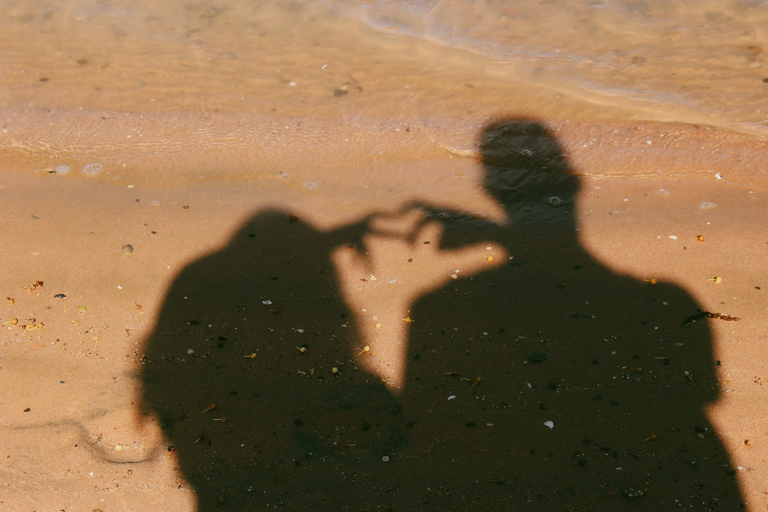 photo of shadows of two people making a heart together with their hands