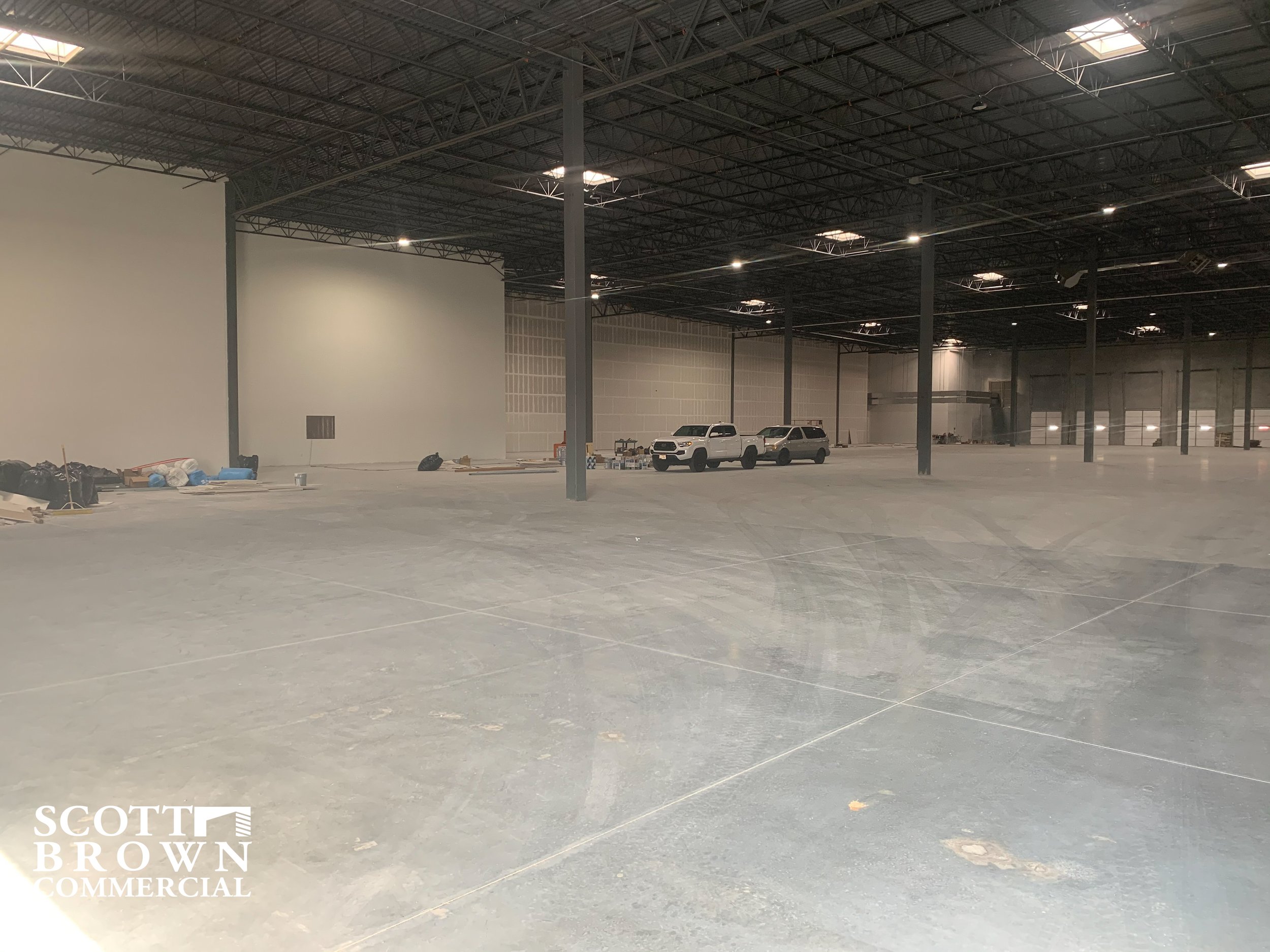  inside 1550 N Western Blvd with concrete floors and a couple pickup trucks 