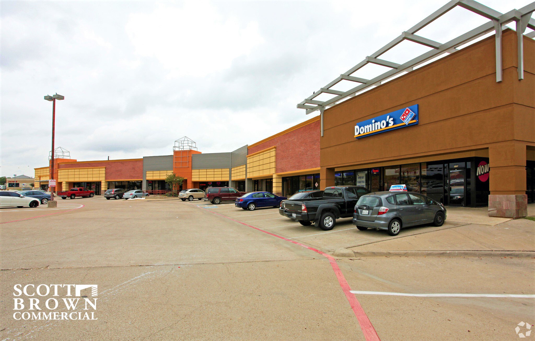  the orange, red brick, and grey building at 2220 Marsh Lane with cloudy sky 