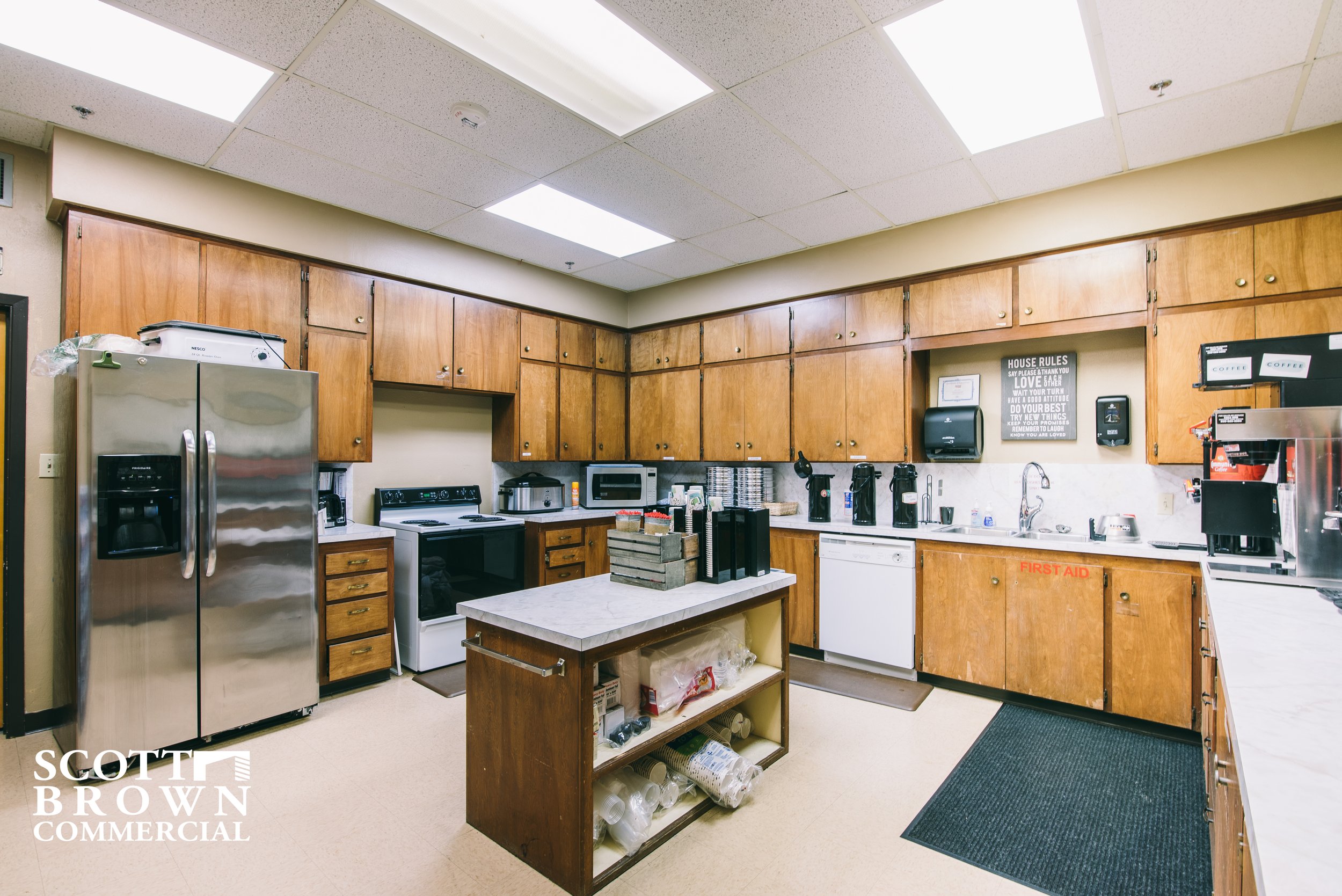  a fully loaded and functional kitchen with fridge, stove, sink, and other appliances with cabinets wrapping all the way around the U shaped room 
