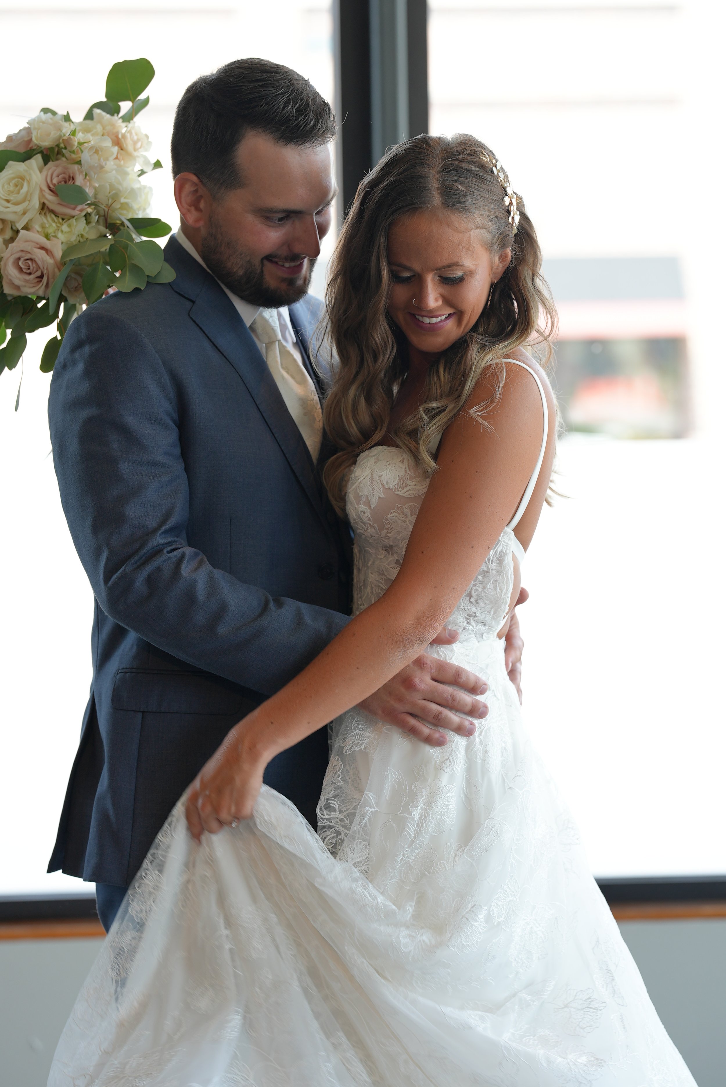 Bride and groom embracing beside a window on their wedding day