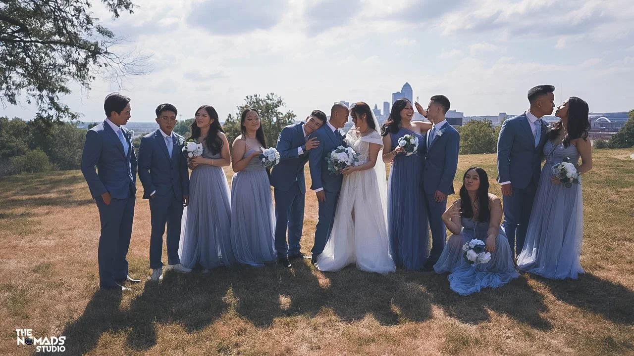 Group of people in wedding attire posing outdoors with city skyline in the background.