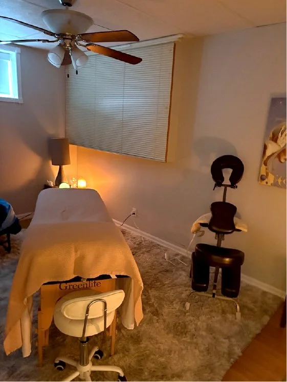 dimply lit room with a massage table and massage chair