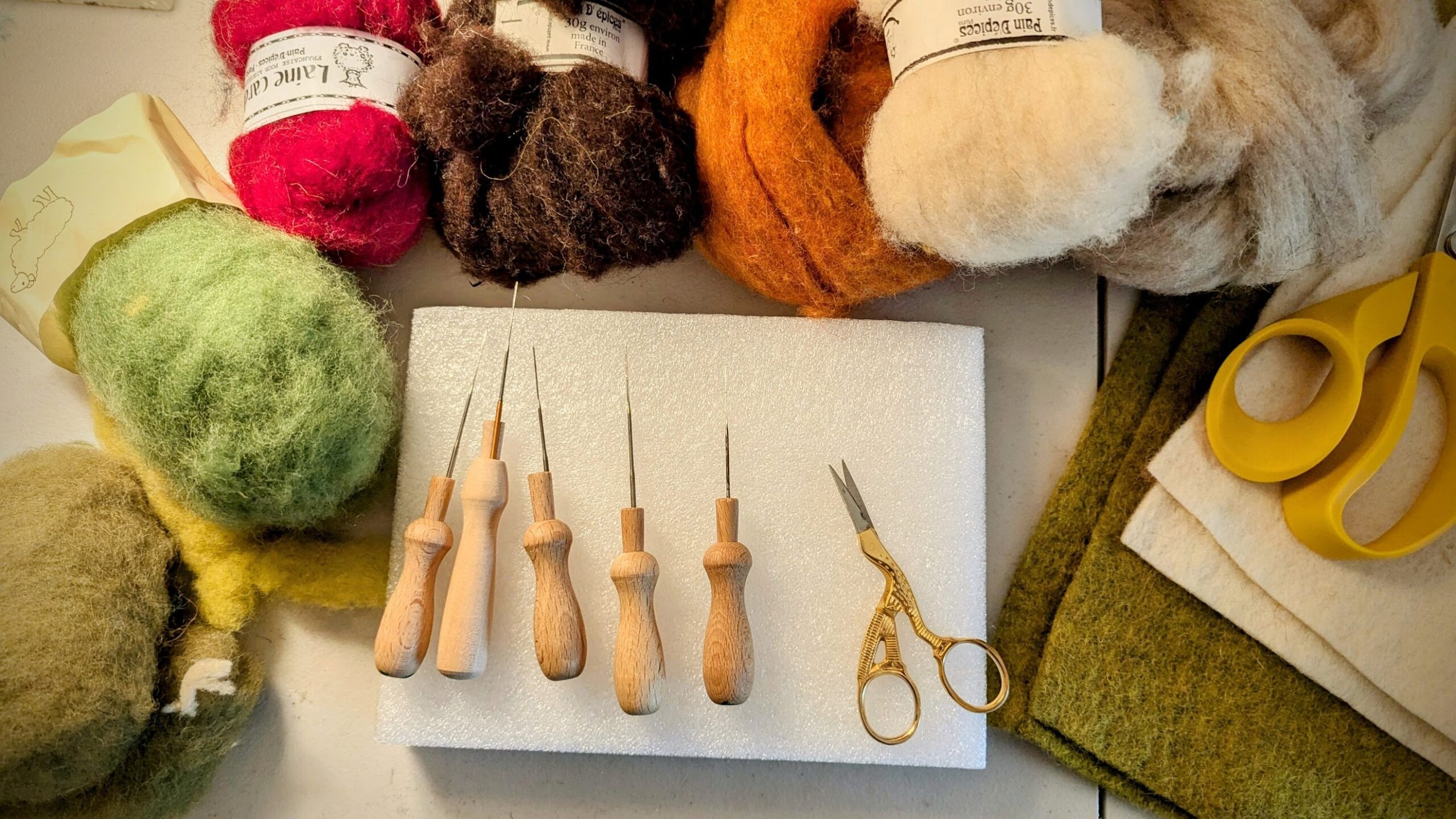Photo of colourful wool and felt pieces surrounding Needle Felting tools