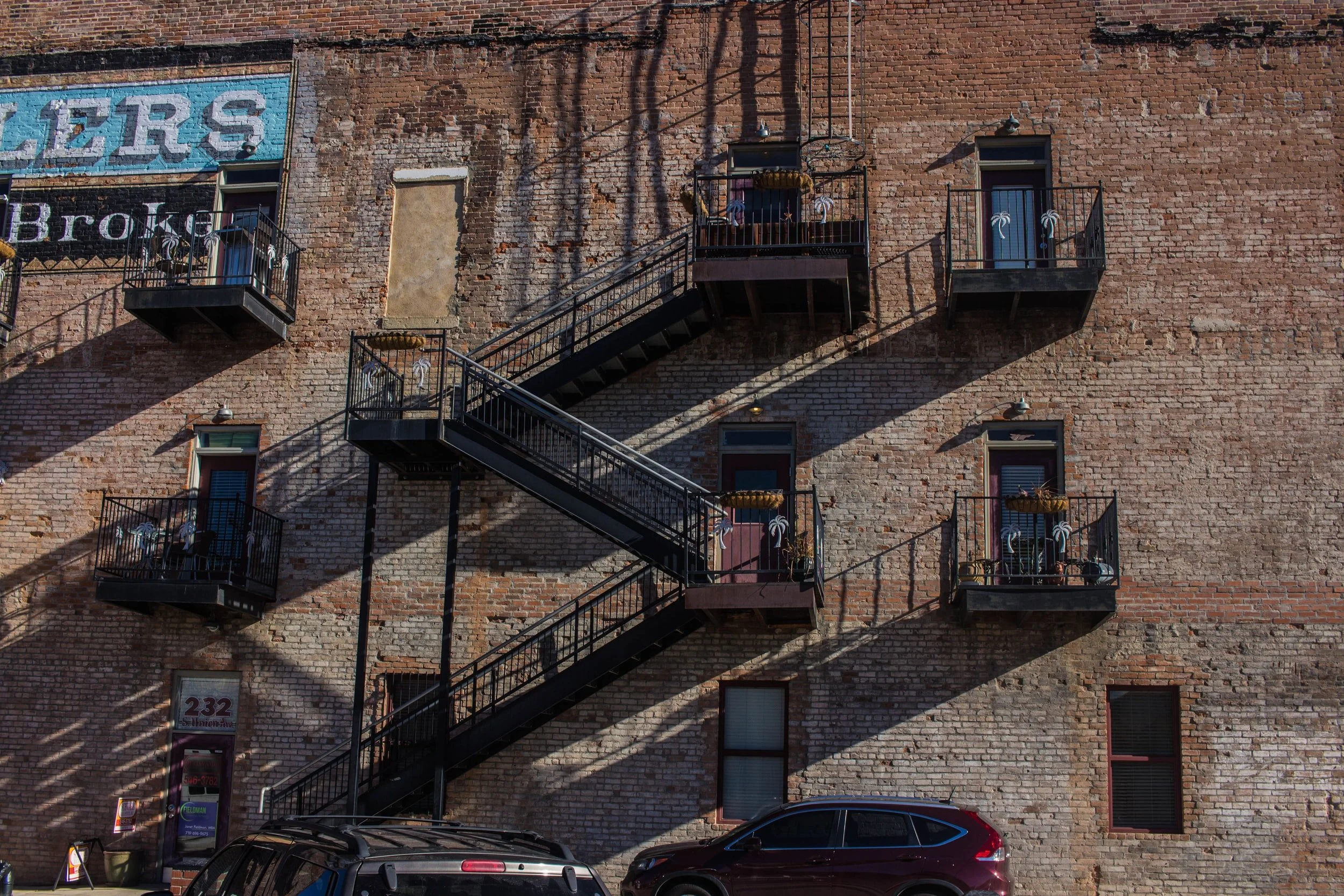 Fire escape ladders on the side of a multilevel brick building