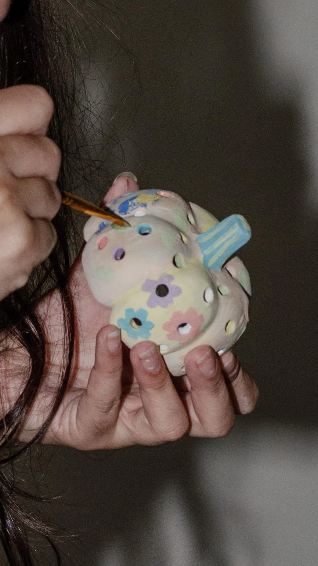 Person painting a ceramic piggy bank with floral designs.