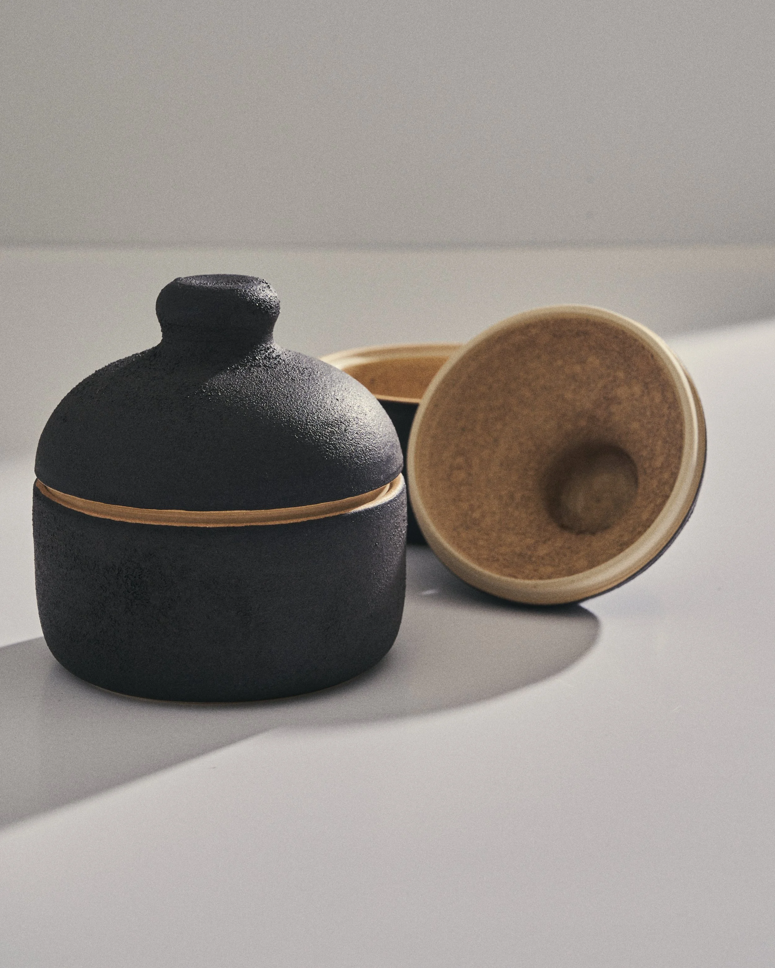 Black ceramic lidded jar with a textured surface and narrow opening