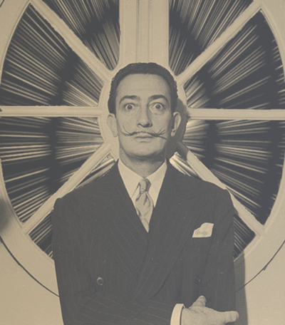 The artist known as, Dali, in a suit standing in front of a large circular window with radiating panes, symbolizing boundless creativity.