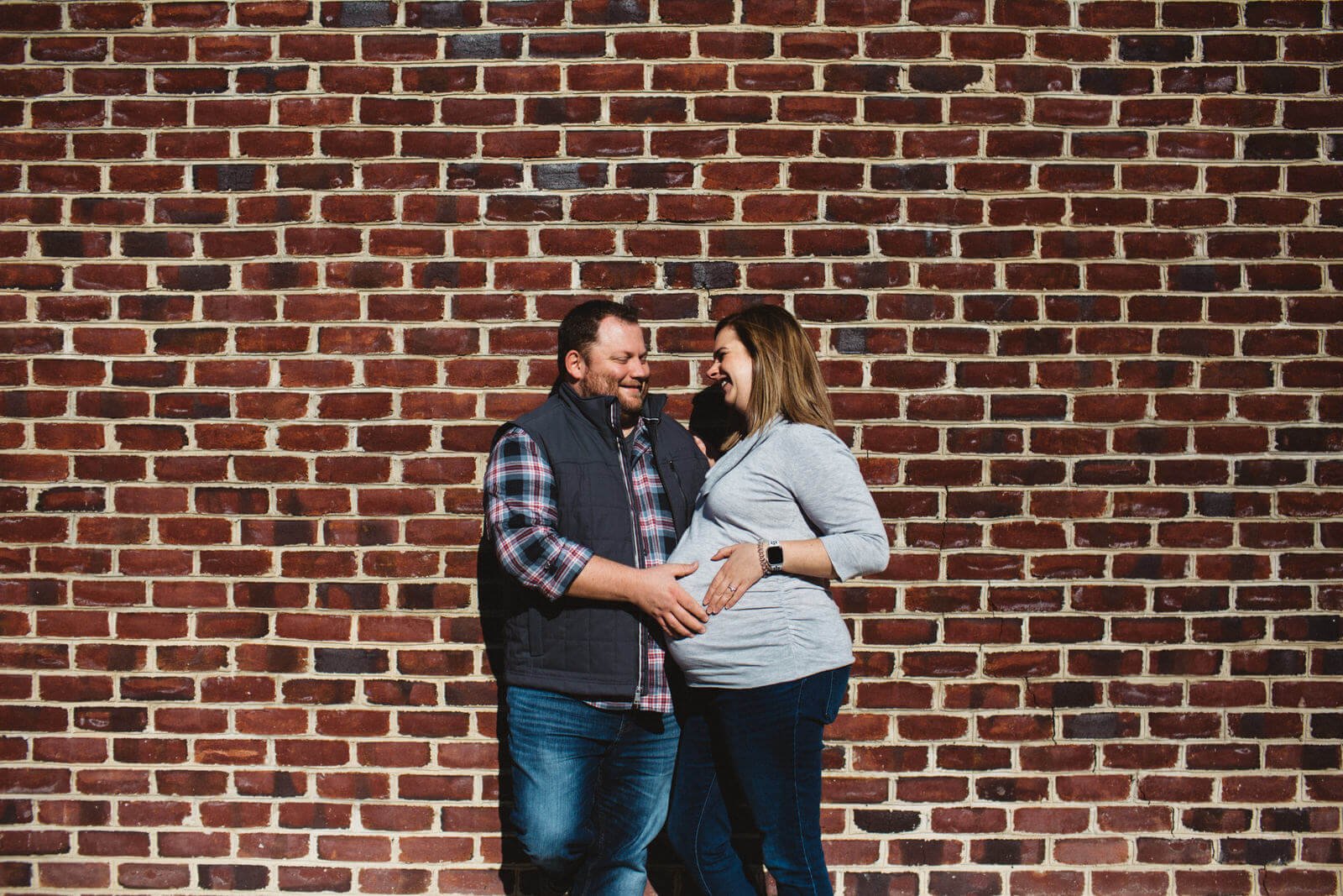  Couple standing by a brick wall for a Washington DC maternity photoshoot 
