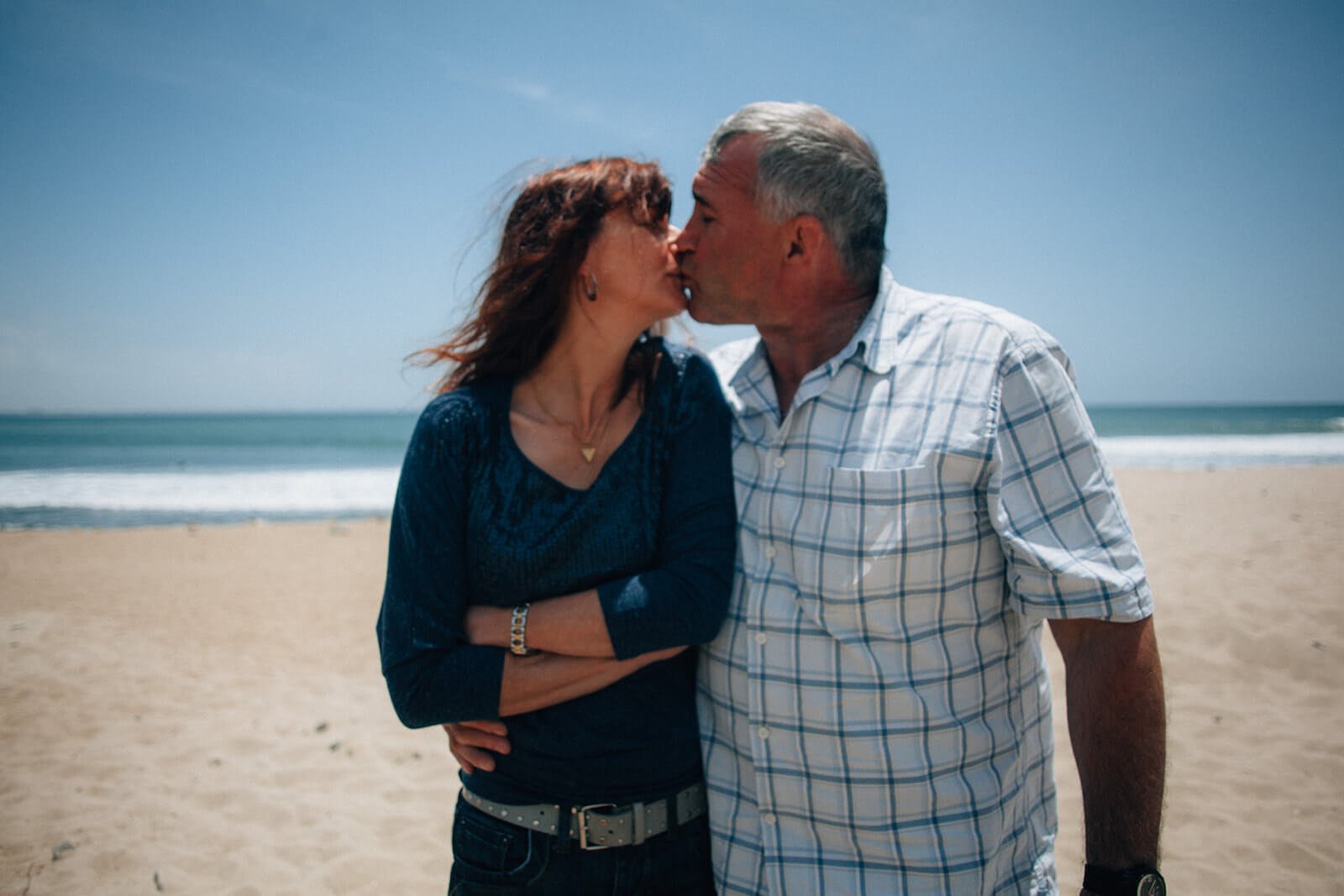 Couple kissing on the beach for a family photo session 