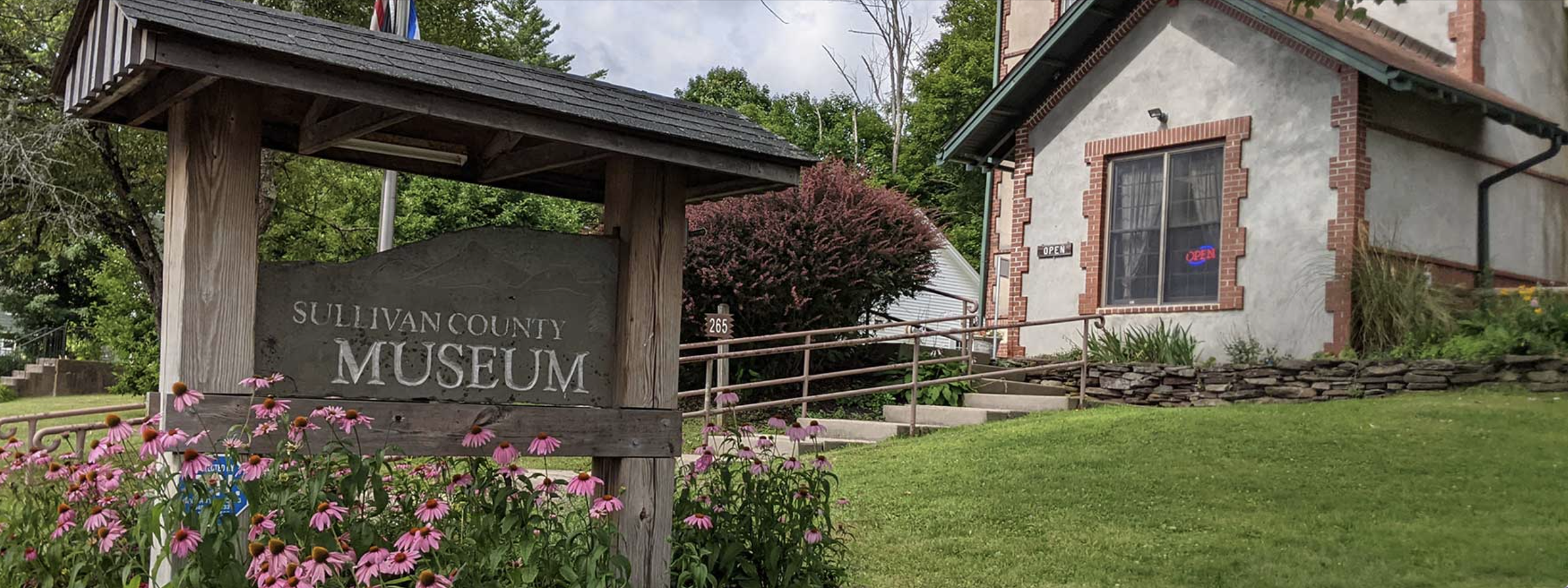 The Sullivan County Museum sign in front of a traditional building with a landscaped garden.