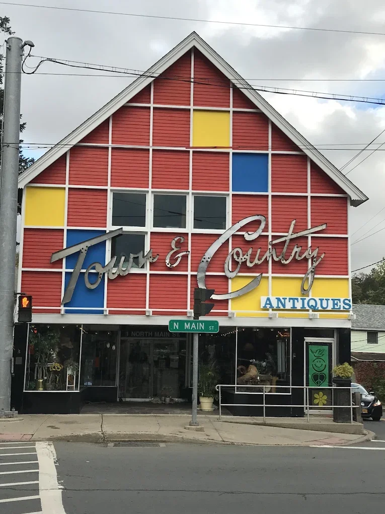 Red building with a colorful facade, signage reading 'Tour & Country Antiques', and a street sign for North Main Street.