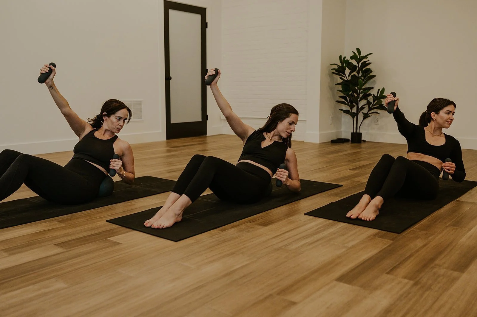 Three woman doing side crunch in Pilates class in Rochester