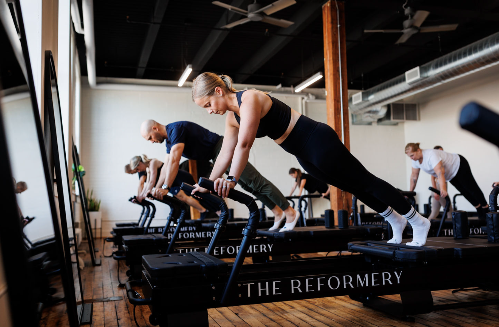 People in plank position on Pilates reformer