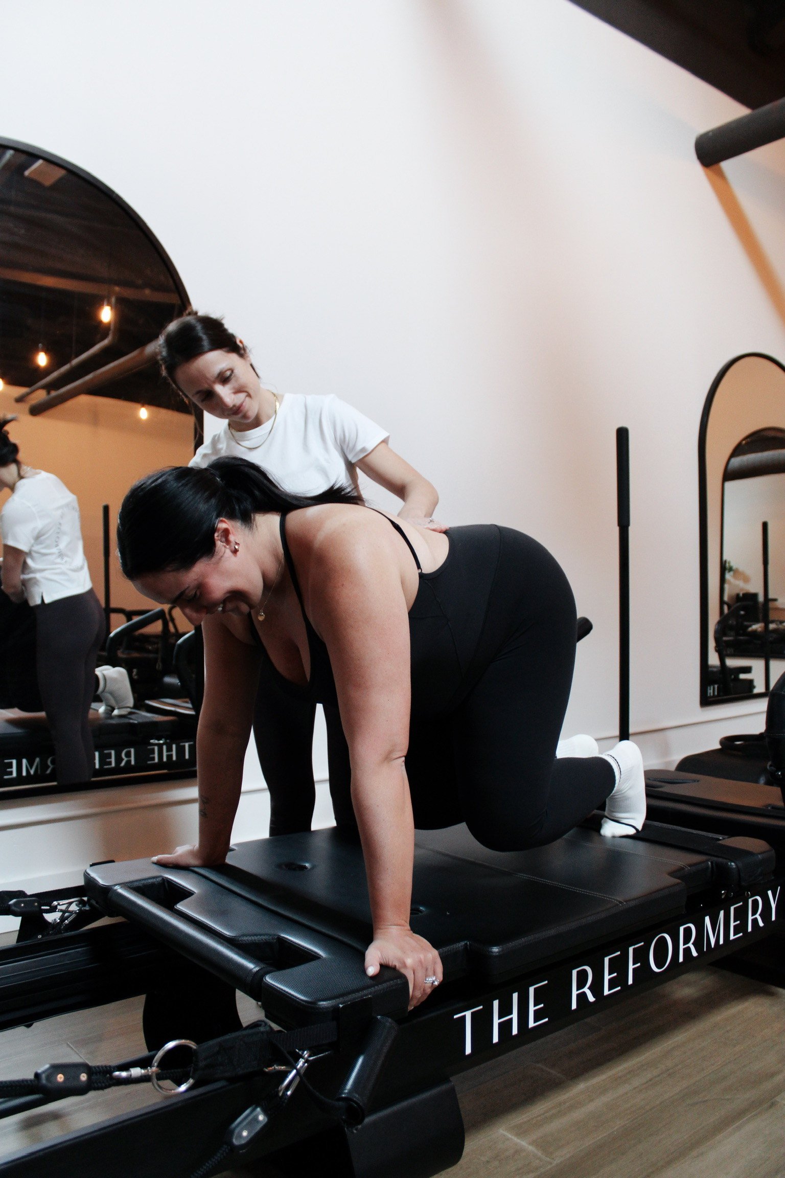 Woman and coach practicing resistance training on Pilates reformer