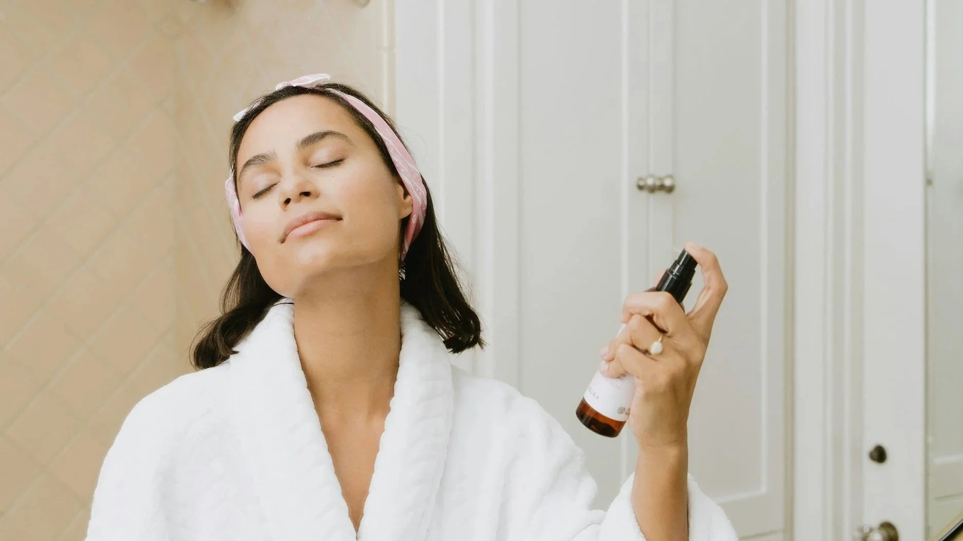 Woman applying skincare as part of a consistent at-home routine for adult acne.