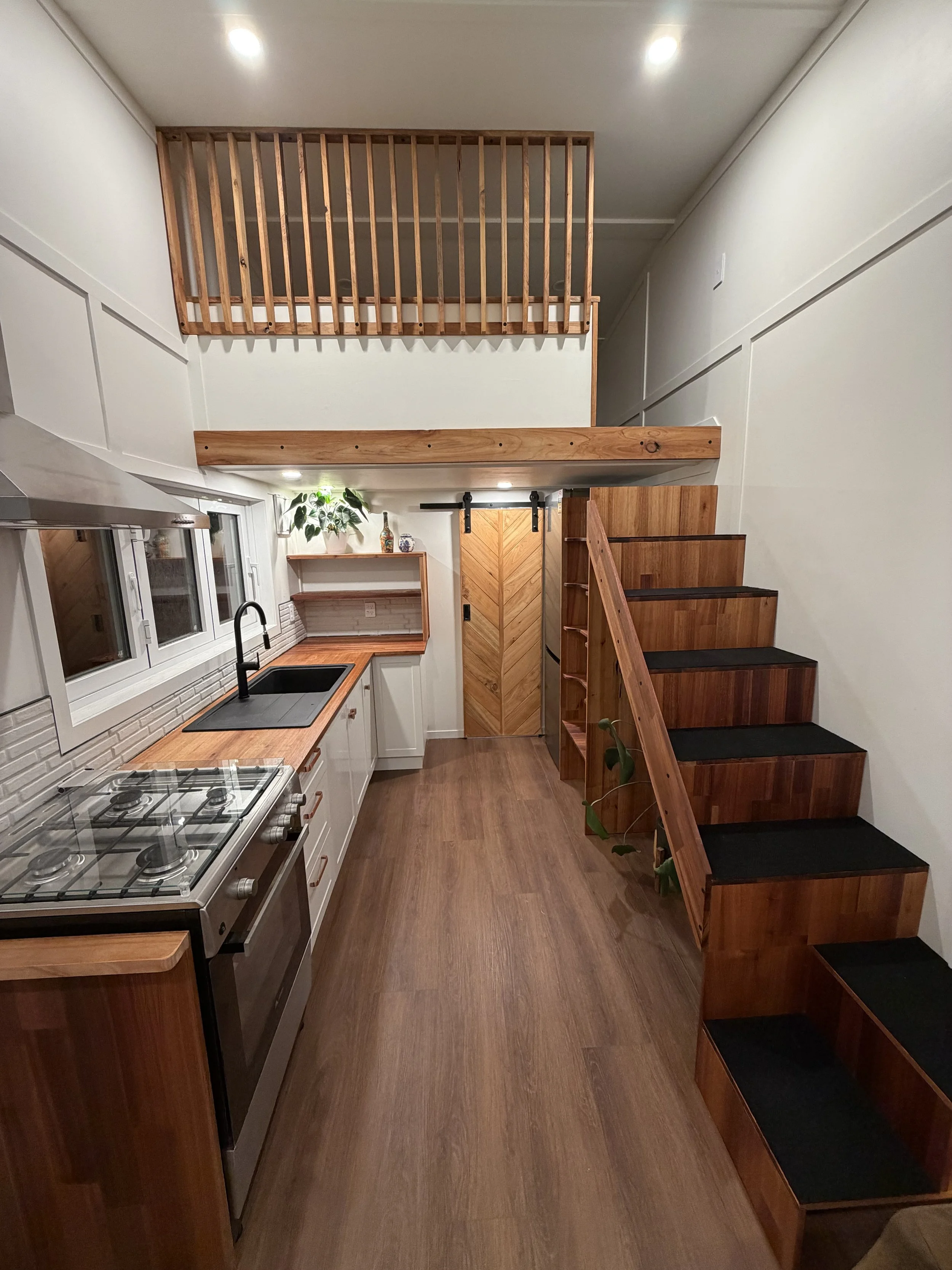 Tiny Timber Homes rental full kitchen view, loft and timber staircase in evening light