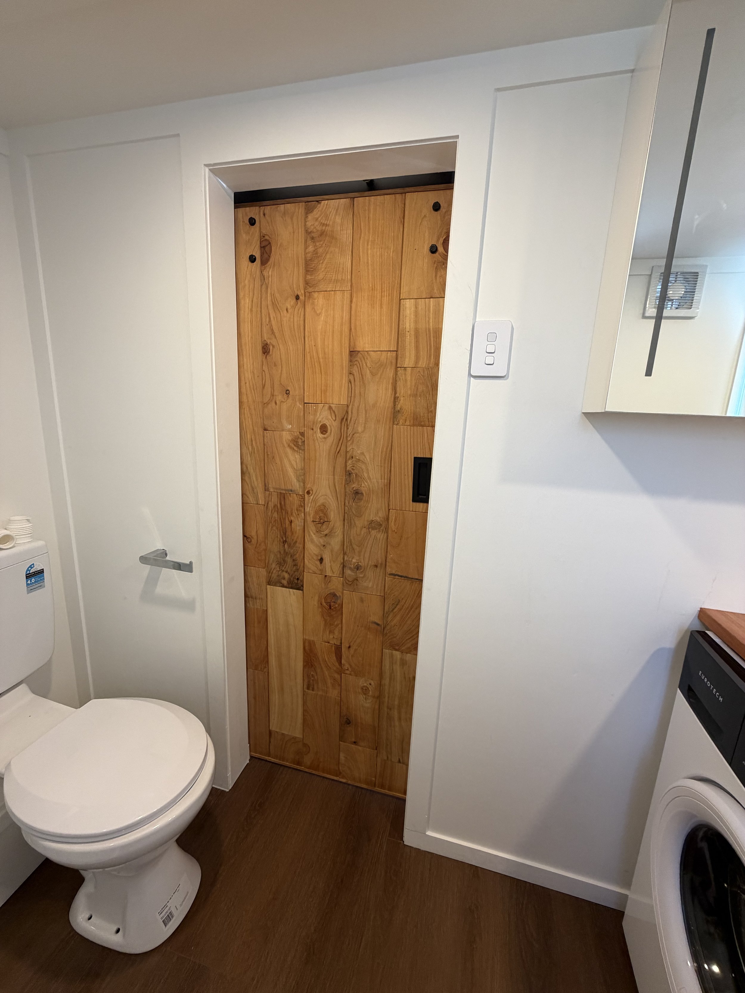 Tiny Timber Homes rental toilet area with timber sliding barn door and laundry nook