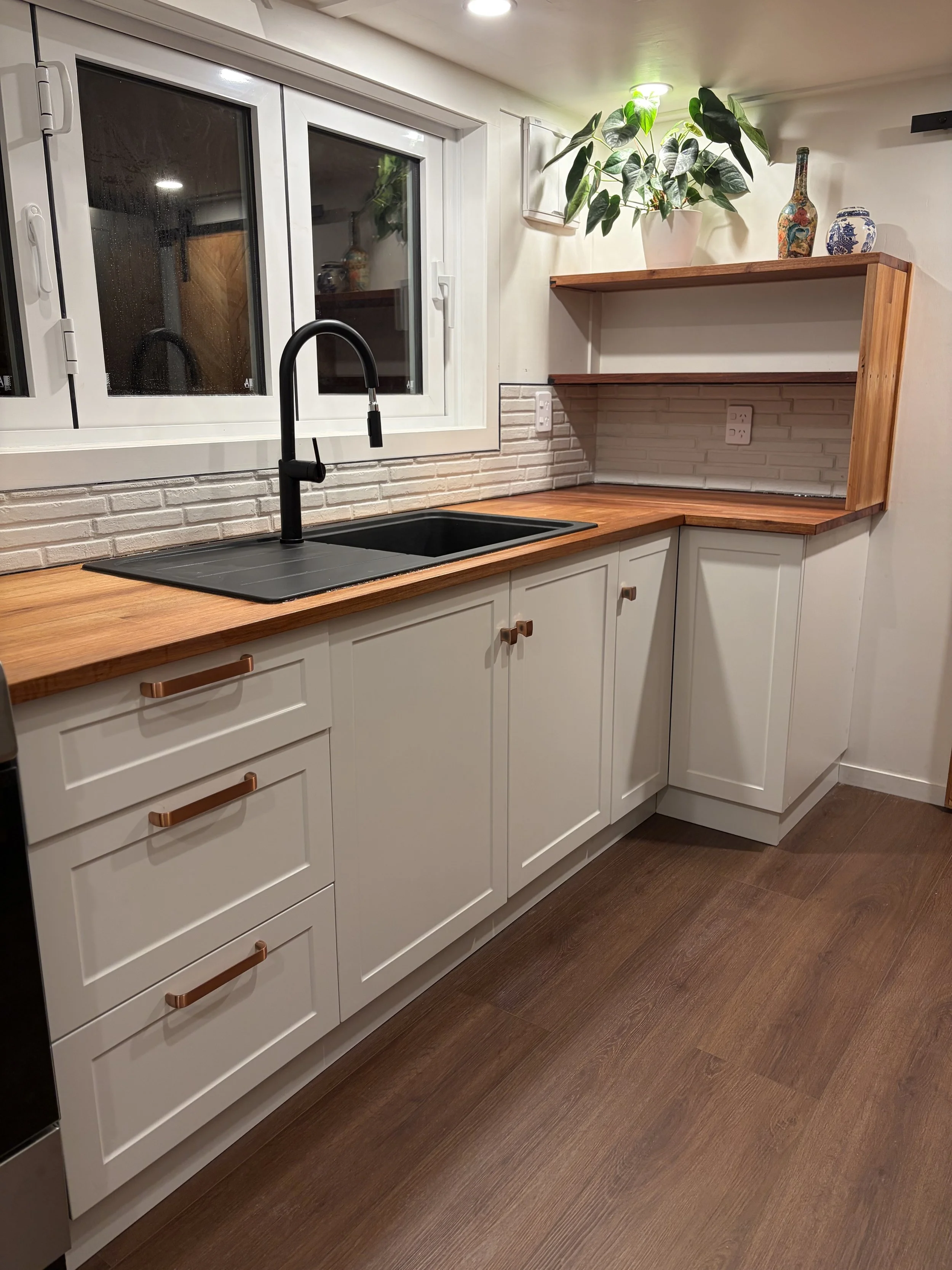 Tiny Timber Homes rental kitchen with black sink, timber benchtop, and open shelving