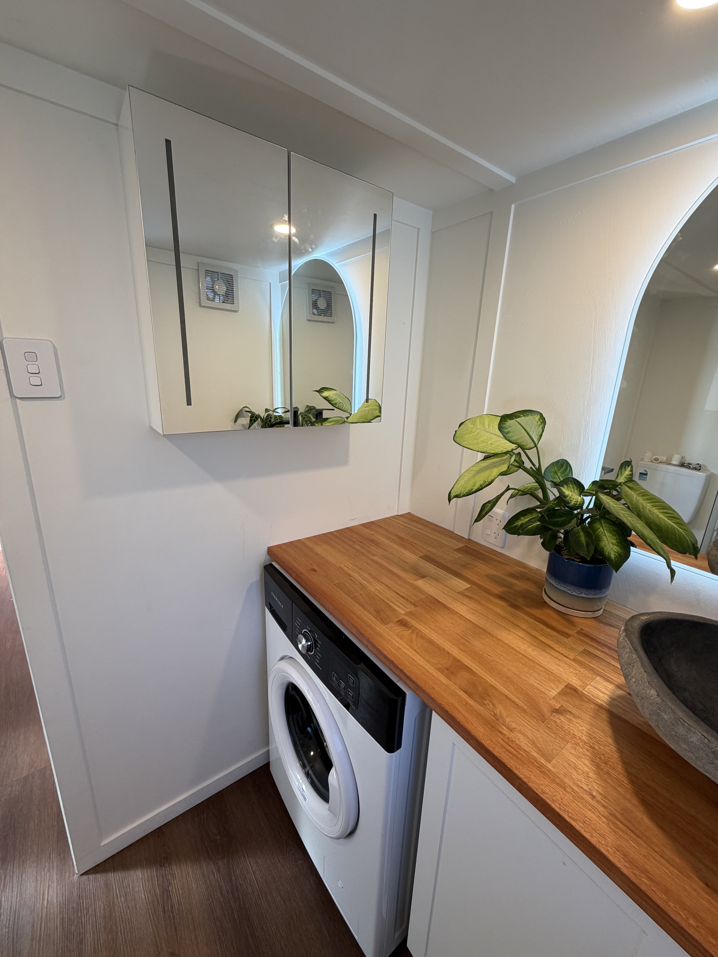 Tiny Timber Homes rental bathroom with mirrored cabinet, timber vanity, and washing machine