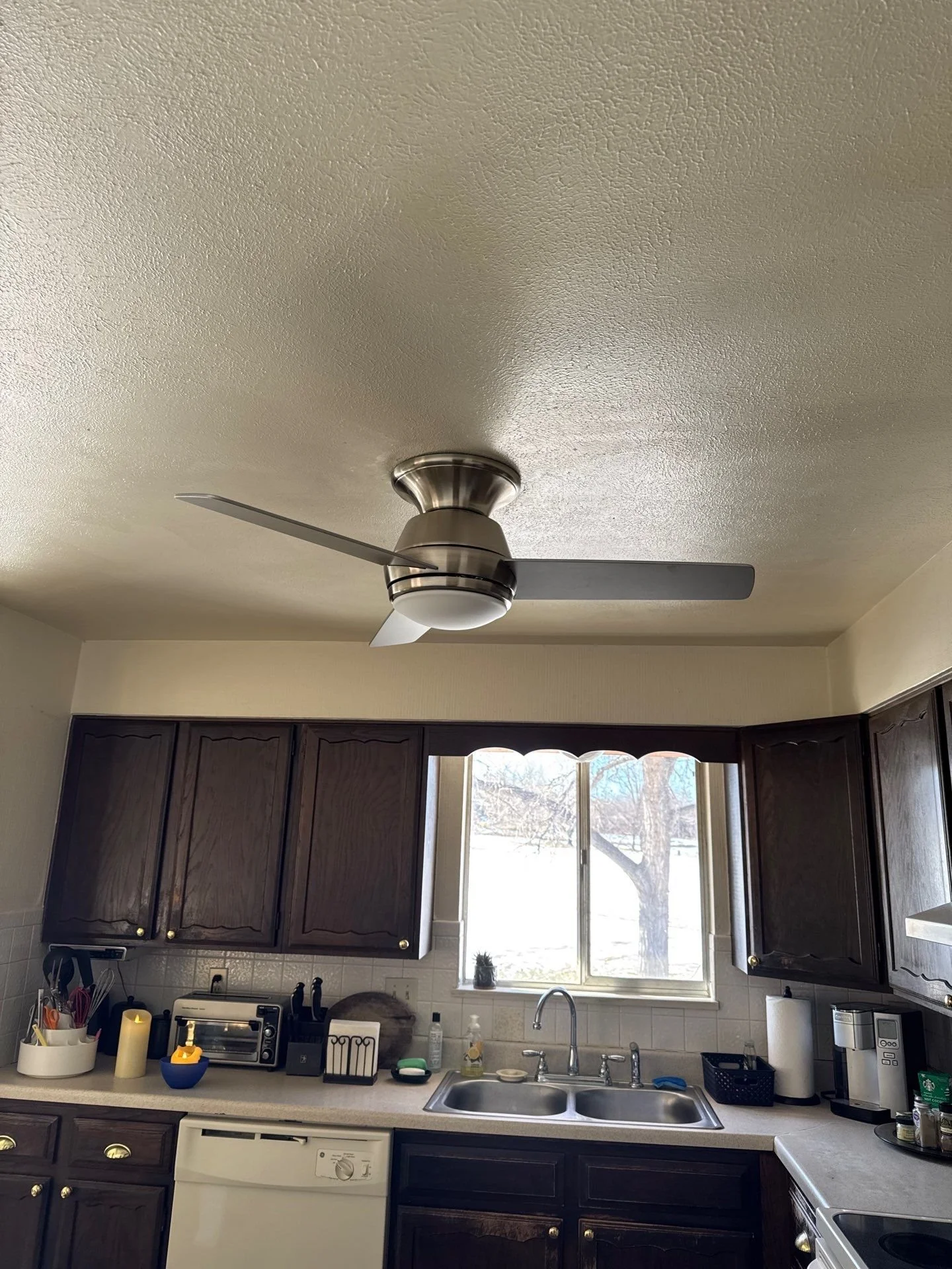 Professional handyman installing a modern ceiling fan in a living room in Arvada, Colorado