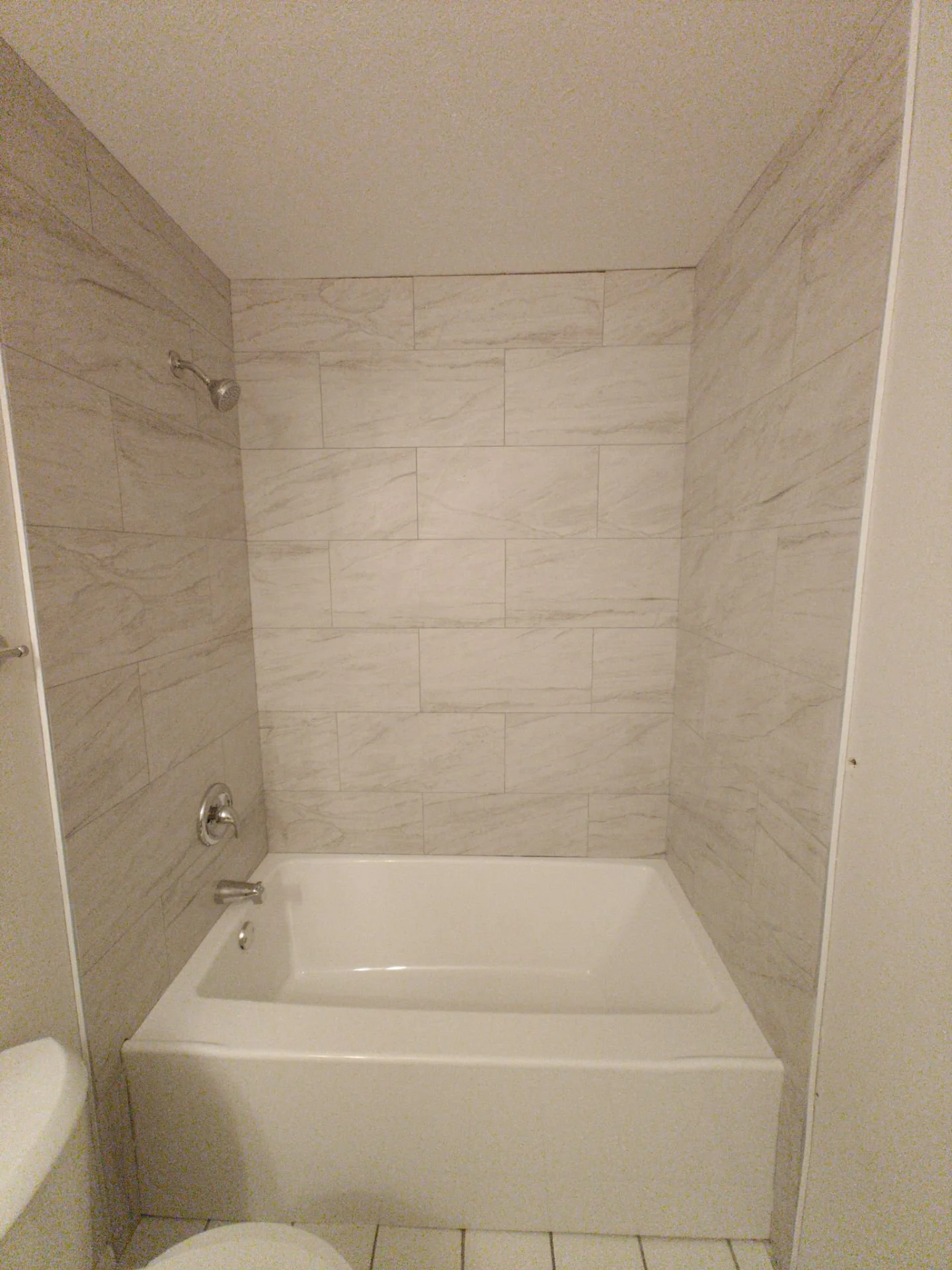 Gray TrafficMaster ceramic tile installed around a new bathtub during a tub surround replacement in Arvada Colorado.