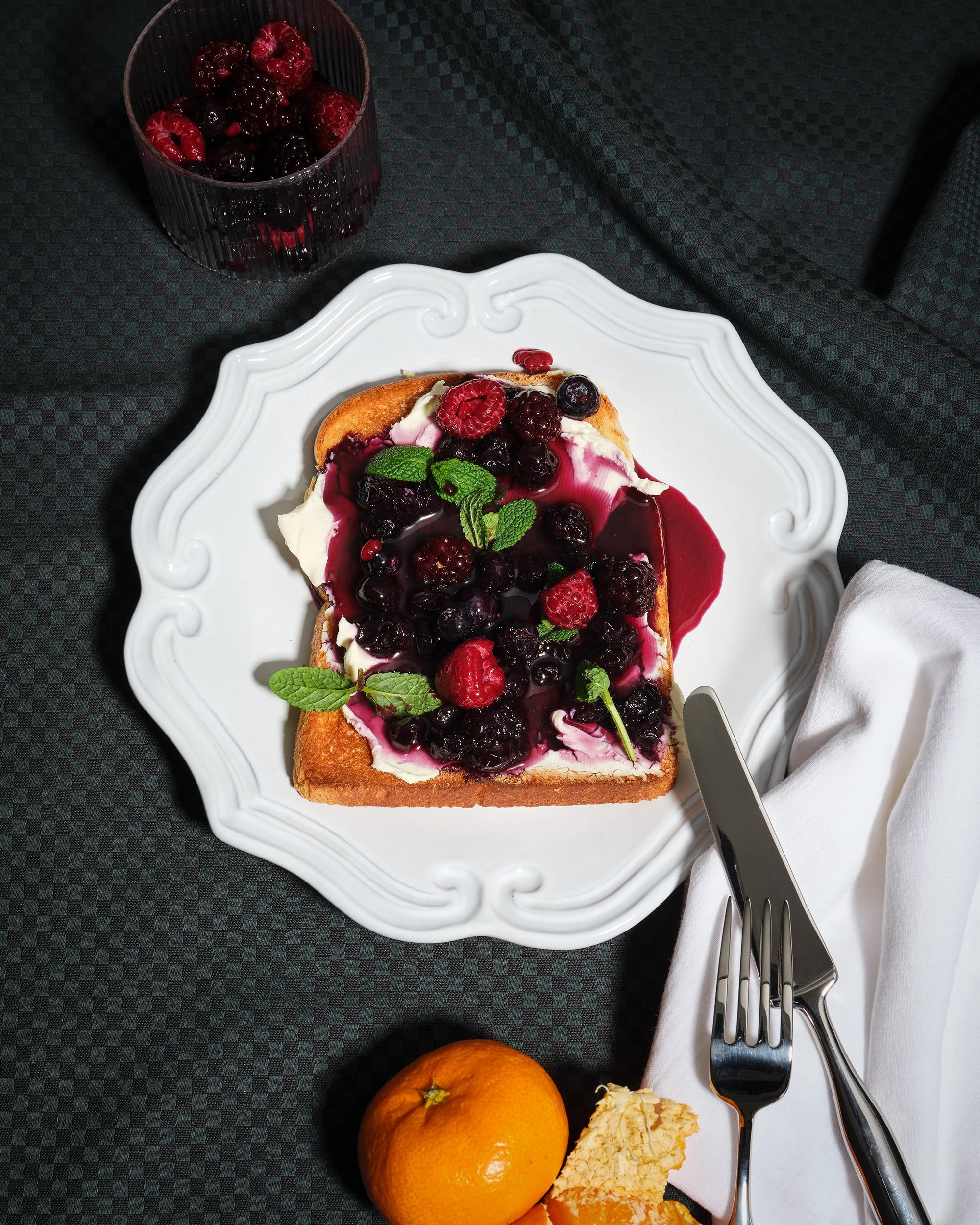 크림치즈와 믹스 베리 콤포트를 올린 토스트. 고급스러운 무드의 음식 사진 연출.