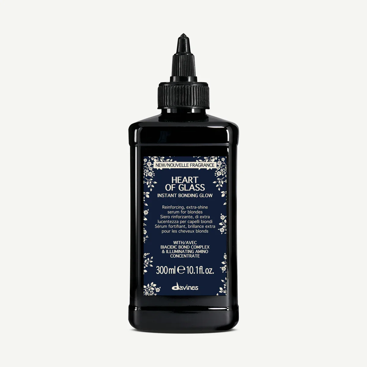 A black bottle of Davines Heart of Glass hair serum with a pump top, featuring a navy blue label with white floral designs and text.