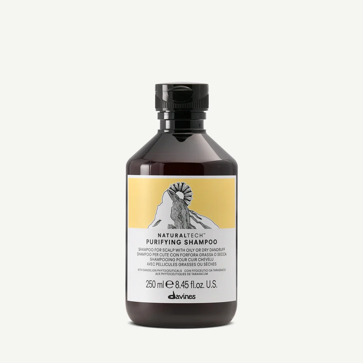 A bottle of Davines Natural Tech Purifying Shampoo with a mountain and sun illustration on the label.