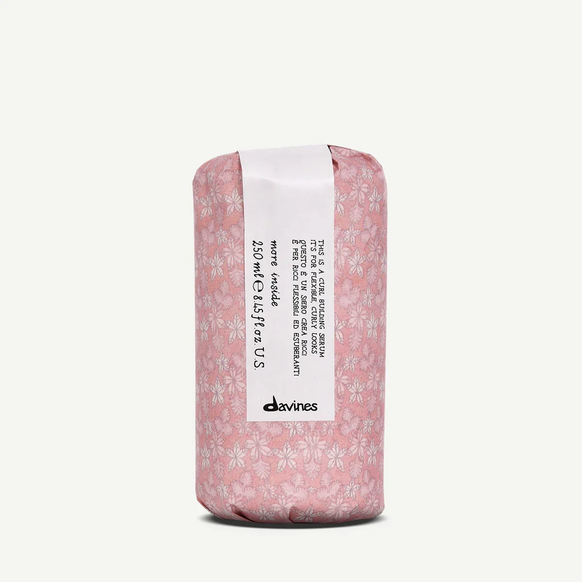 A pink soap wrapped in floral patterned paper with a white label featuring product information and the Davines brand name.