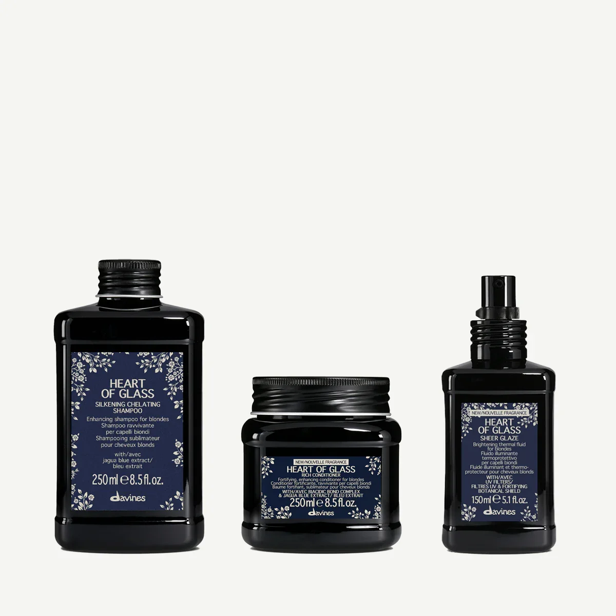 Three black bottles of Davines hair care products with blue labels: shampoo on the left, conditioner in the middle, and a spray on the right, all with floral design on the labels.