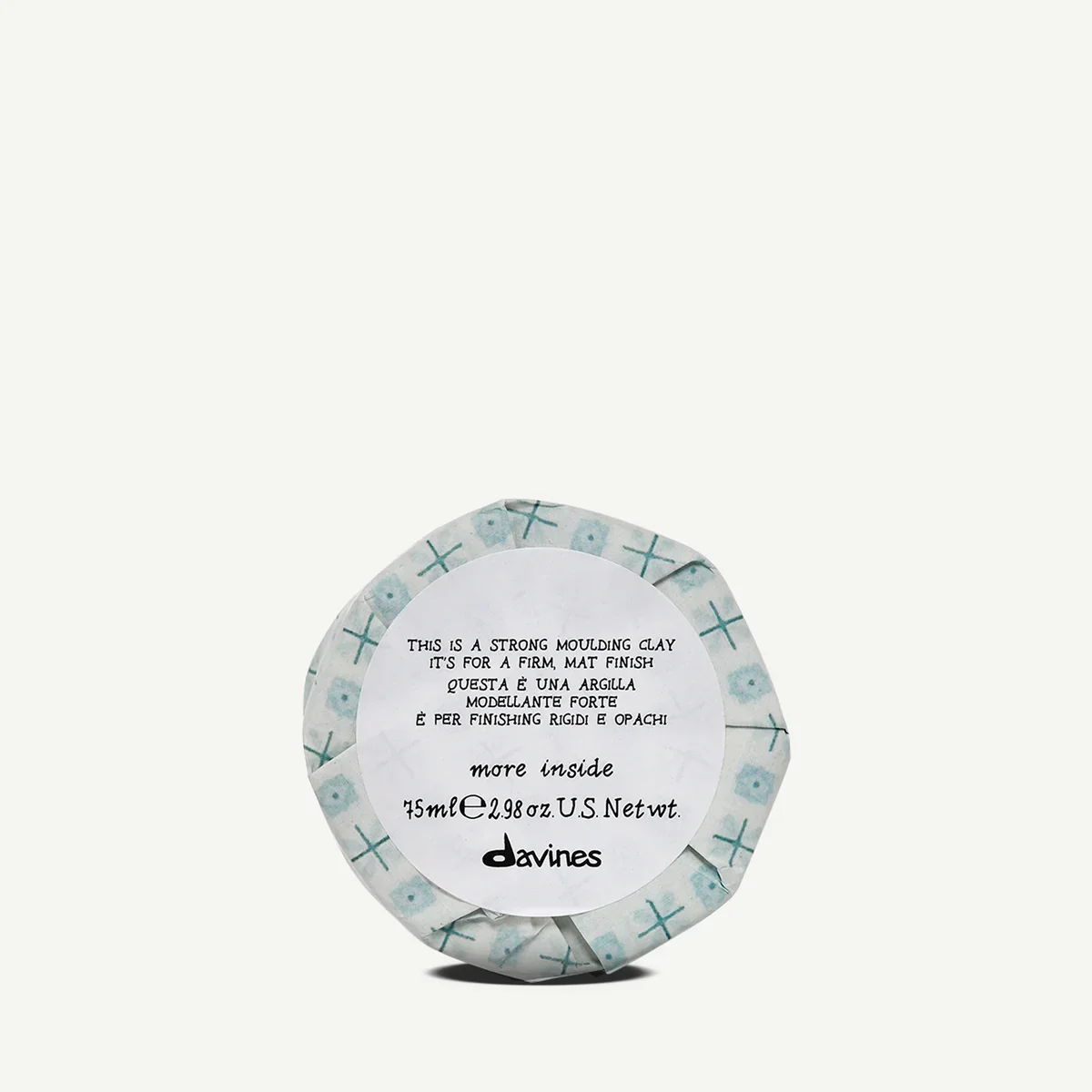 A round container of strong molding clay with a patterned paper wrapper, featuring a label with instructions in English, Italian, and Portuguese, and the brand name 'davines' at the bottom.