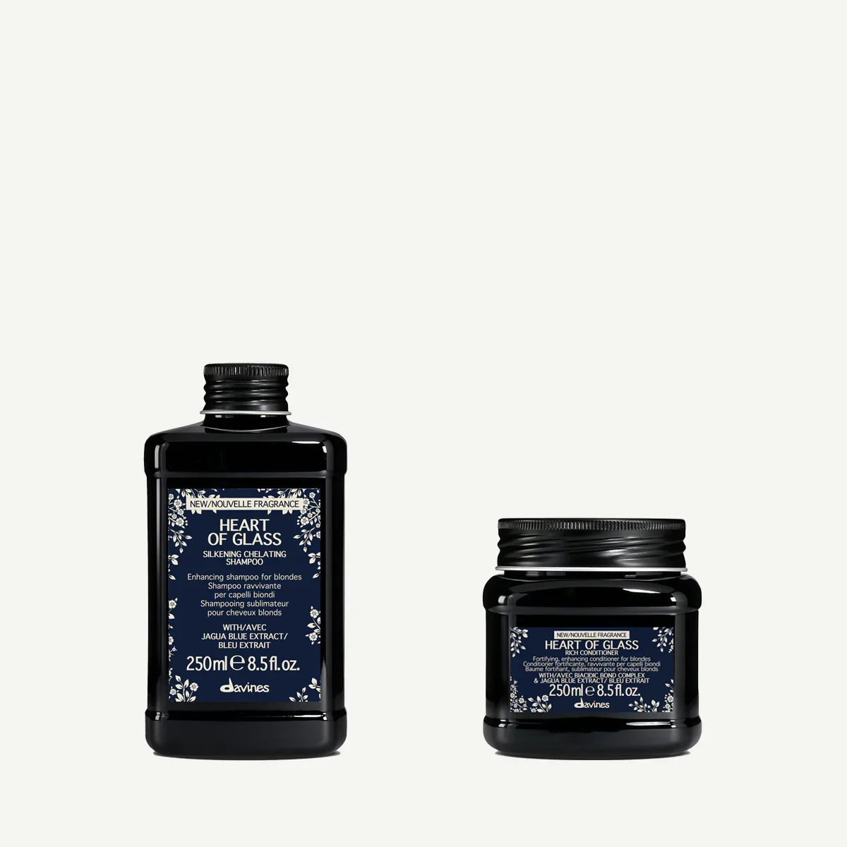 Two black containers of Davines Heart of Glass hair products, a shampoo bottle and a conditioner jar, with blue and white labels featuring floral designs.
