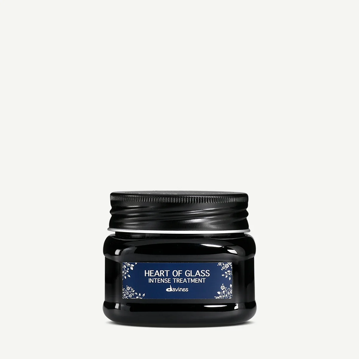 Black jar of 'Heart of Glass' intense treatment by Davines with a dark blue label and decorative white floral design.