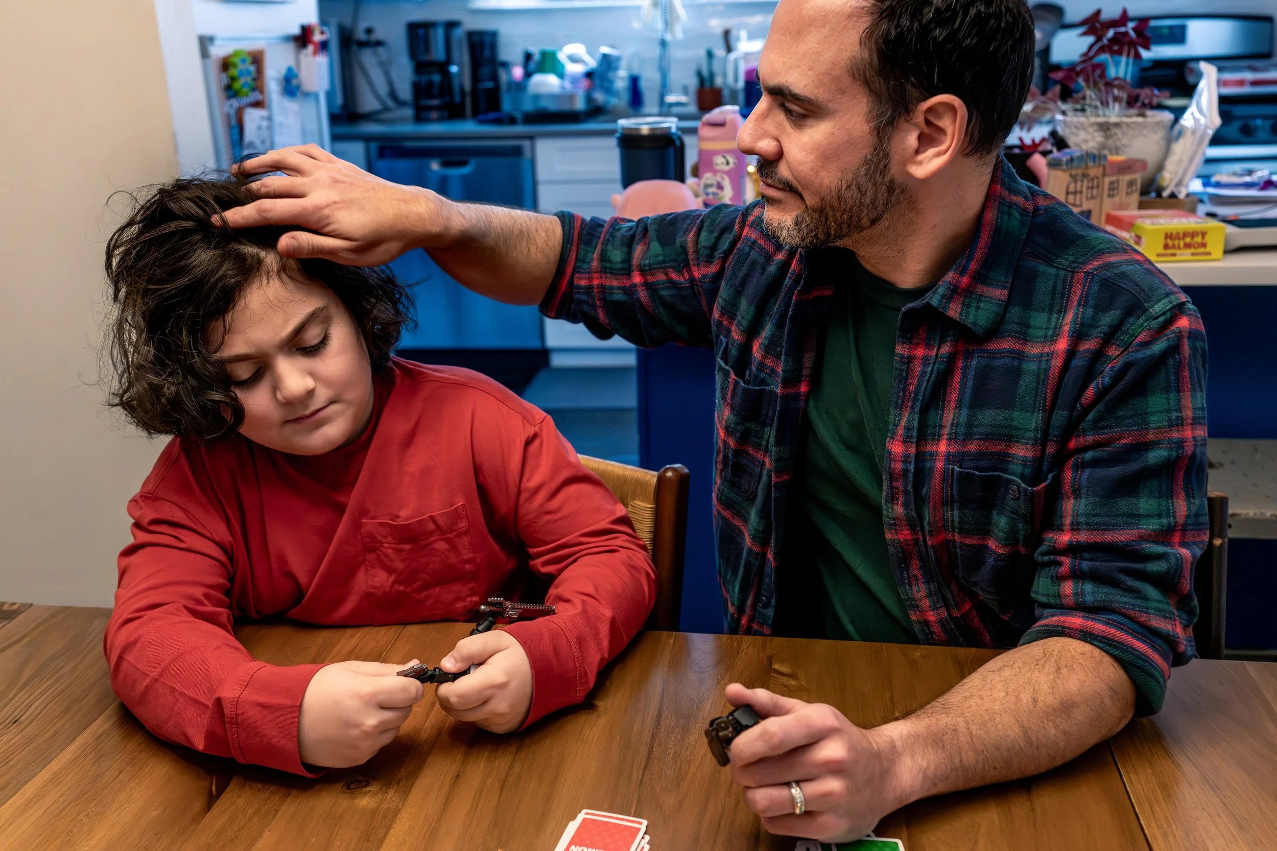 documentary family photography father gently brushing aside son's hair while sitting at a table